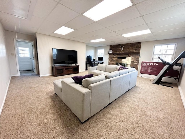 living room with carpet flooring, a drop ceiling, and a brick fireplace