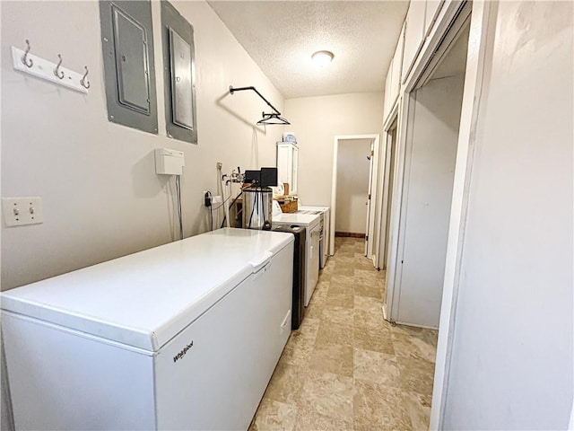 clothes washing area featuring a textured ceiling, separate washer and dryer, and electric panel