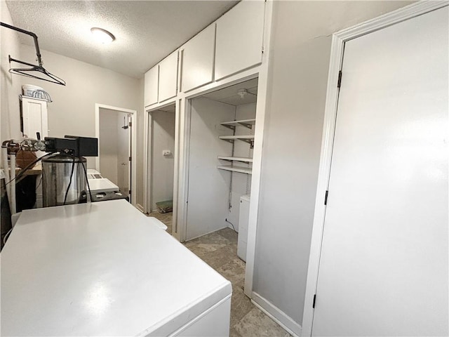 interior space with cabinets, a textured ceiling, and washing machine and clothes dryer