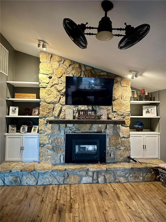 unfurnished living room with a stone fireplace, wood-type flooring, and vaulted ceiling