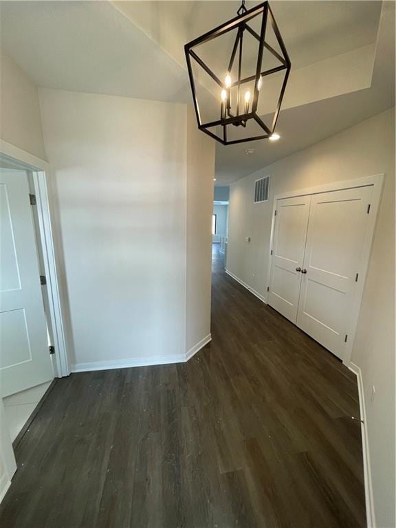 unfurnished dining area with a notable chandelier and dark wood-type flooring