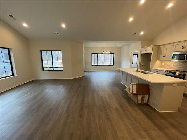 kitchen featuring vaulted ceiling, appliances with stainless steel finishes, white cabinetry, sink, and a kitchen island with sink