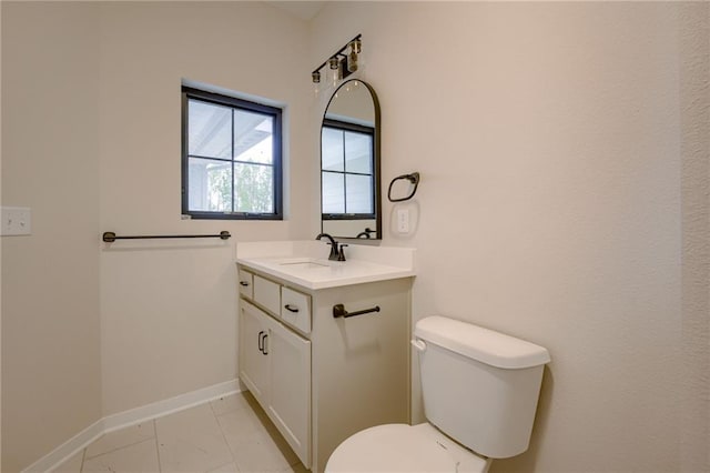 half bath with toilet, baseboards, marble finish floor, and vanity
