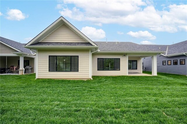 rear view of property with a patio, a shingled roof, and a yard