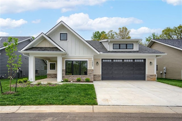 craftsman-style home with concrete driveway, board and batten siding, stone siding, and a front lawn