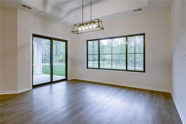 unfurnished room featuring baseboards, visible vents, and dark wood finished floors