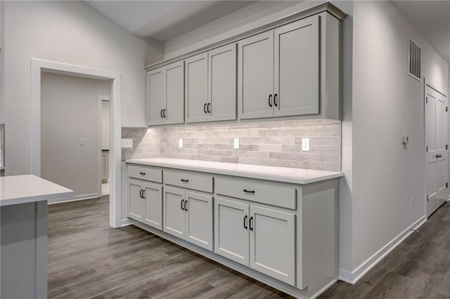 kitchen with light countertops, gray cabinetry, tasteful backsplash, and dark wood-type flooring