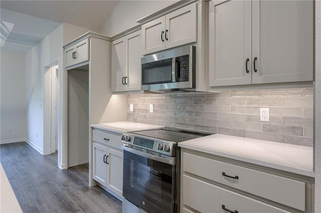 kitchen featuring light countertops, decorative backsplash, appliances with stainless steel finishes, and wood finished floors