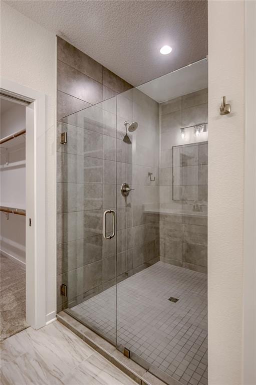 full bath with marble finish floor, recessed lighting, a textured ceiling, a spacious closet, and a stall shower