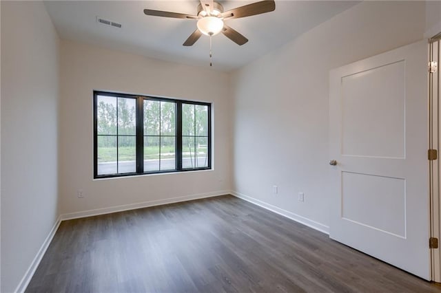 empty room with visible vents, baseboards, ceiling fan, and dark wood-style floors