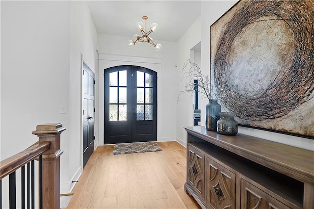 foyer entrance featuring french doors, a notable chandelier, and light wood-type flooring