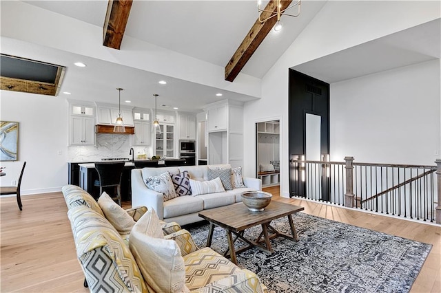 living room featuring beamed ceiling, high vaulted ceiling, and light wood-type flooring