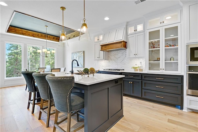 kitchen featuring hanging light fixtures, white cabinetry, an inviting chandelier, custom exhaust hood, and appliances with stainless steel finishes