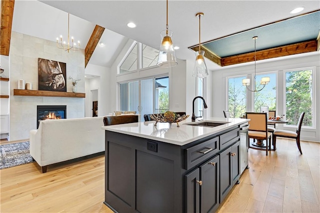 kitchen with a large fireplace, an island with sink, and hanging light fixtures