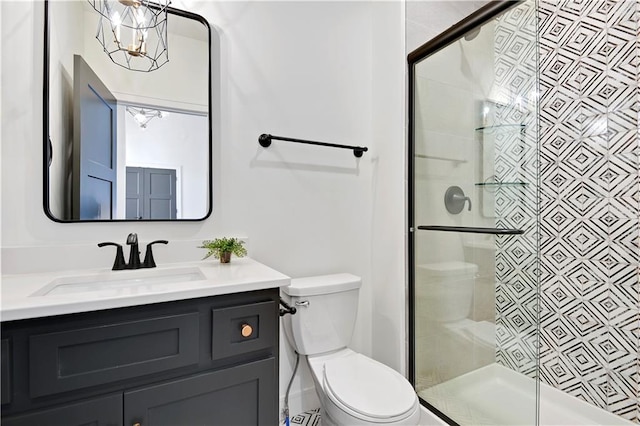 bathroom with vanity, toilet, a shower with shower door, and an inviting chandelier