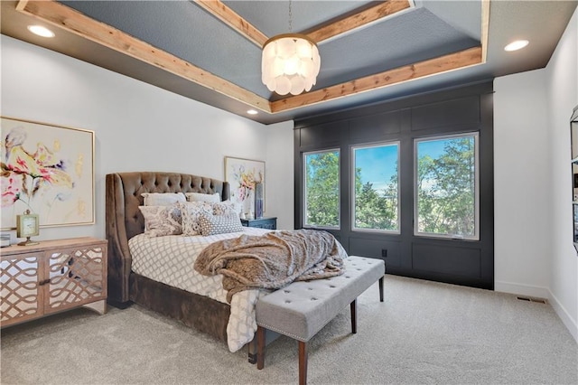 bedroom with light colored carpet and a tray ceiling