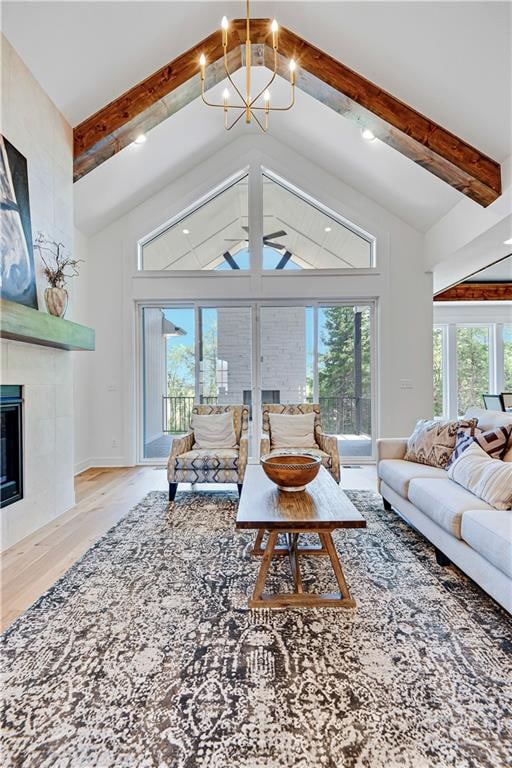 living room with a healthy amount of sunlight, light hardwood / wood-style floors, lofted ceiling with beams, and a tile fireplace