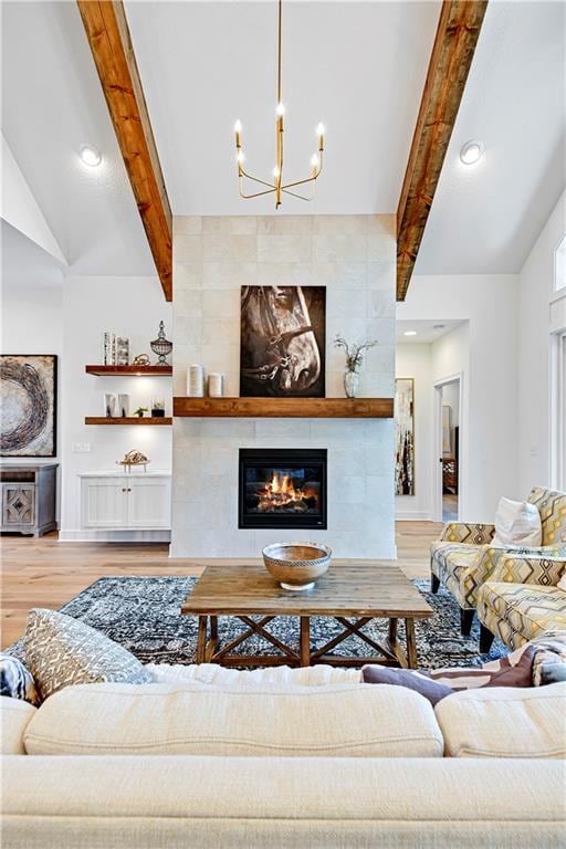 living room featuring a notable chandelier, hardwood / wood-style floors, vaulted ceiling with beams, and a tiled fireplace