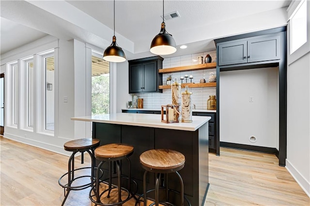 bar featuring light wood-type flooring, decorative light fixtures, and backsplash