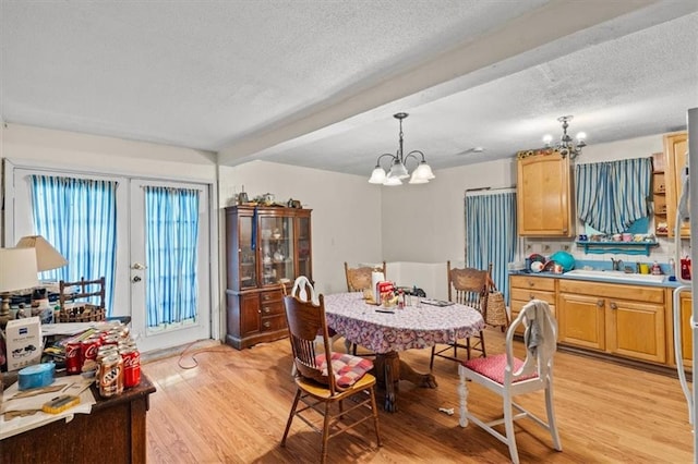 dining area with beamed ceiling, a notable chandelier, a textured ceiling, and light hardwood / wood-style floors