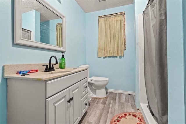 bathroom with hardwood / wood-style floors, a textured ceiling, toilet, vanity, and a shower with curtain