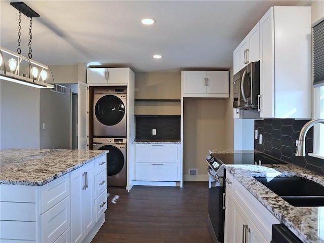 kitchen with stacked washer and dryer, dark hardwood / wood-style floors, stainless steel appliances, decorative light fixtures, and white cabinetry