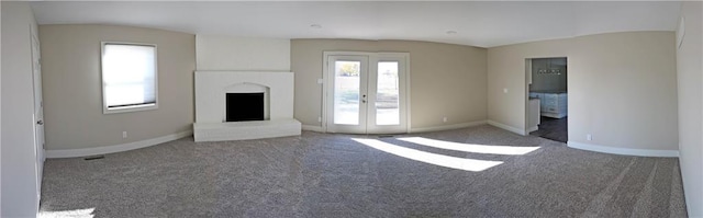 unfurnished living room with french doors, a fireplace, and dark colored carpet