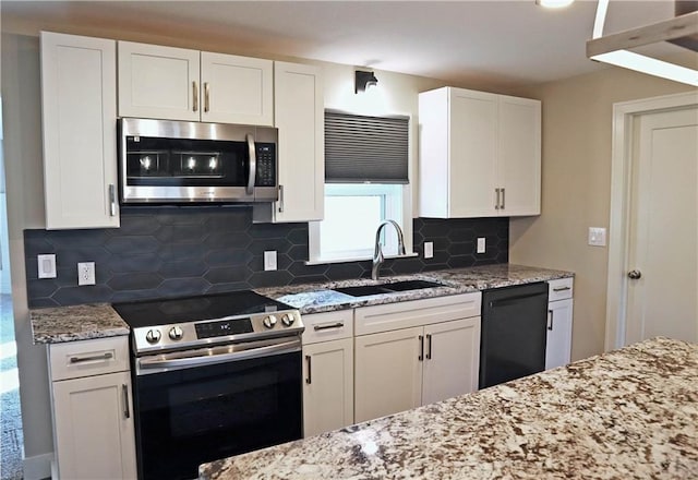 kitchen featuring backsplash, sink, light stone countertops, white cabinets, and appliances with stainless steel finishes