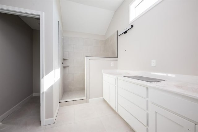 bathroom with a tile shower, tile patterned floors, and lofted ceiling