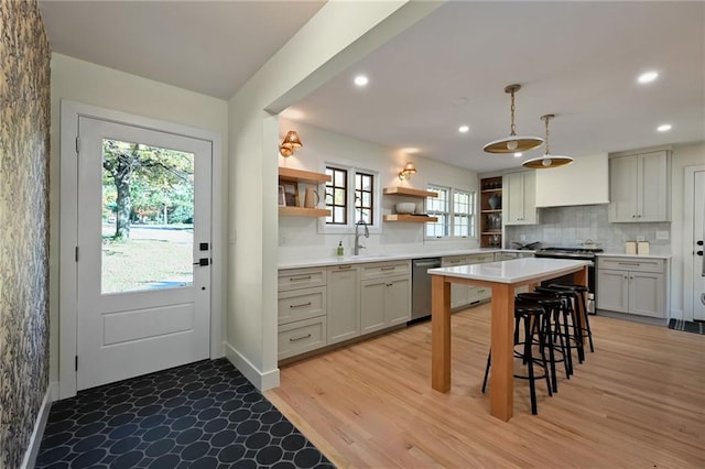 kitchen featuring sink, a kitchen breakfast bar, light hardwood / wood-style floors, decorative light fixtures, and appliances with stainless steel finishes