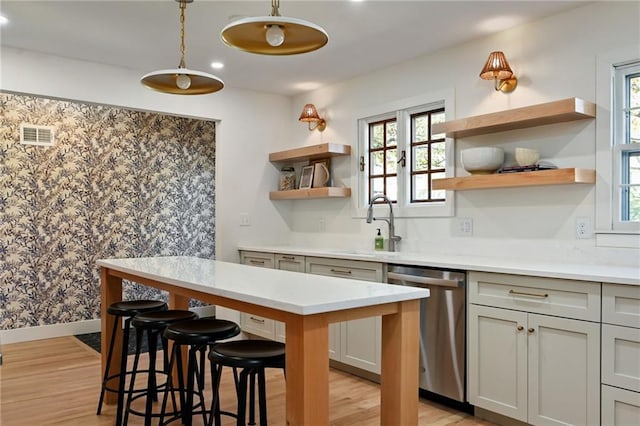 kitchen featuring dishwasher, a kitchen bar, light hardwood / wood-style flooring, and sink