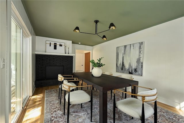 dining area featuring wood-type flooring and a brick fireplace