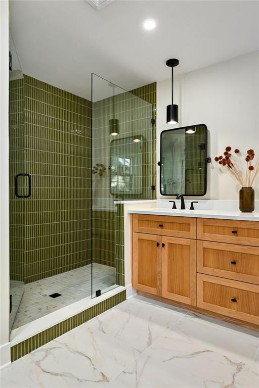 bathroom featuring a shower with door and vanity