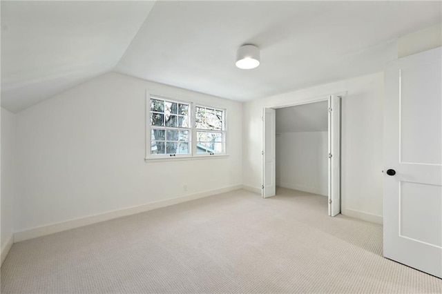 unfurnished bedroom with a closet, light colored carpet, and vaulted ceiling