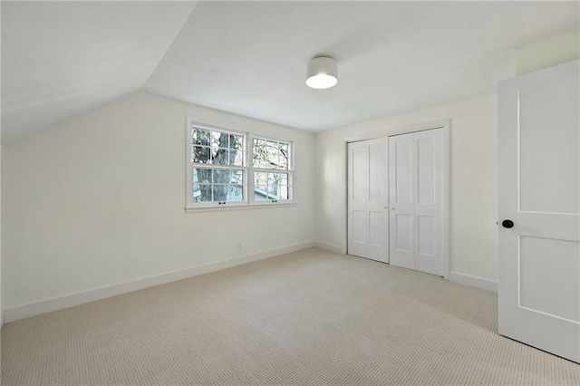 unfurnished bedroom with light carpet, a closet, and vaulted ceiling