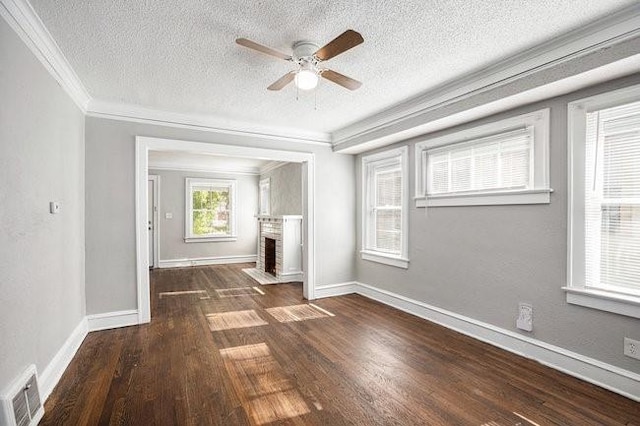 unfurnished living room featuring dark hardwood / wood-style floors, crown molding, a textured ceiling, a fireplace, and ceiling fan