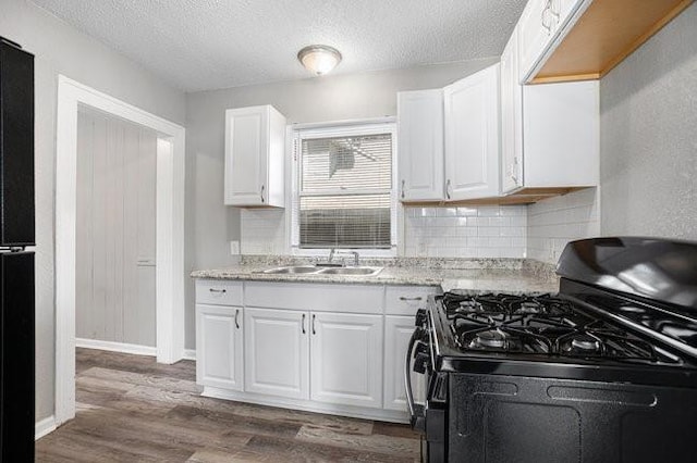 kitchen with sink, black gas stove, a textured ceiling, white cabinets, and dark wood-type flooring