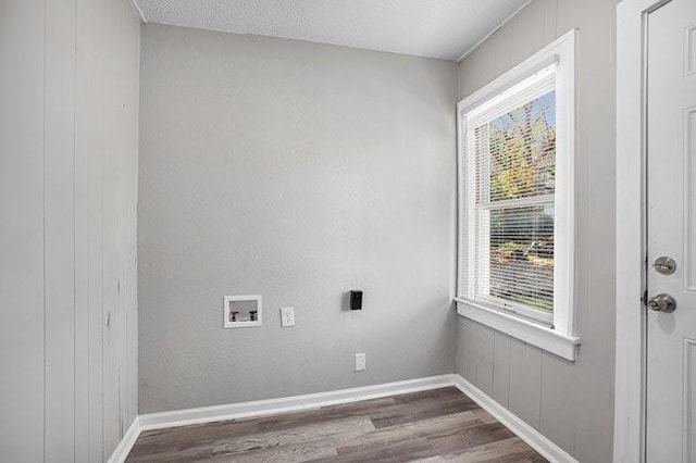 laundry room featuring wood walls, hardwood / wood-style floors, a textured ceiling, and washer hookup