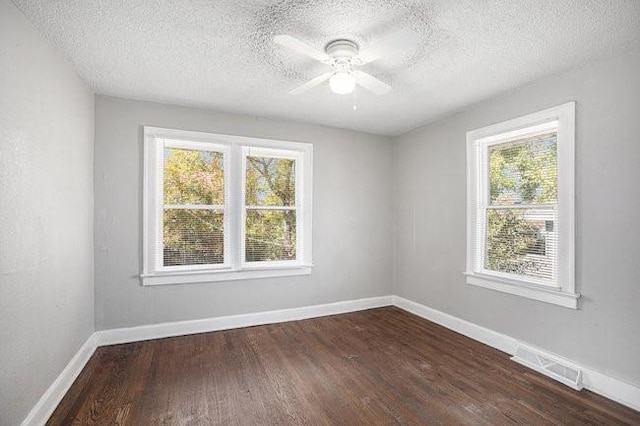 spare room featuring a wealth of natural light, dark wood-type flooring, a textured ceiling, and ceiling fan