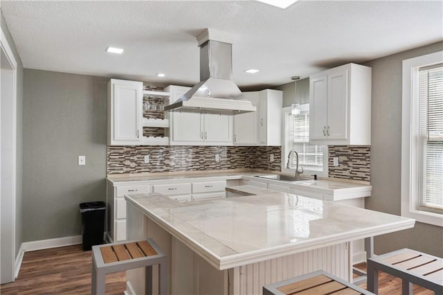 kitchen featuring a breakfast bar area, sink, white cabinets, and island exhaust hood