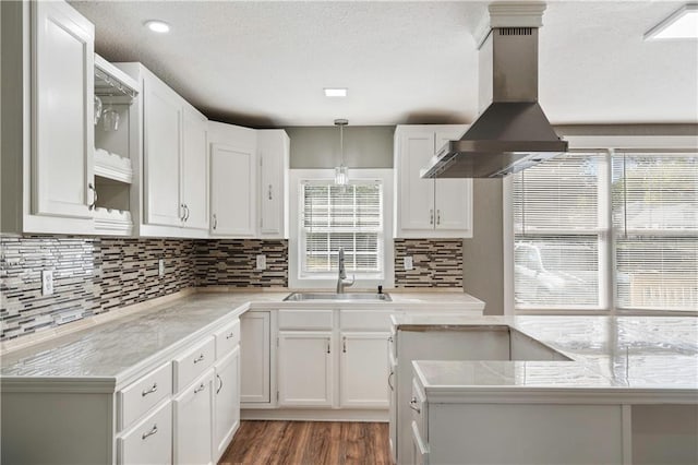 kitchen featuring wall chimney range hood, a healthy amount of sunlight, sink, and pendant lighting