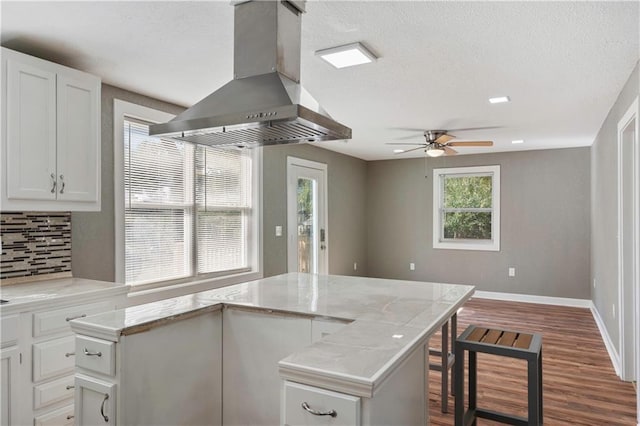 kitchen featuring dark hardwood / wood-style floors, ventilation hood, a center island, white cabinets, and light stone counters