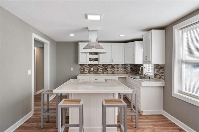 kitchen featuring a breakfast bar, decorative backsplash, sink, and white cabinets