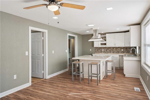 kitchen with sink, a kitchen island, white cabinetry, exhaust hood, and dark hardwood / wood-style floors