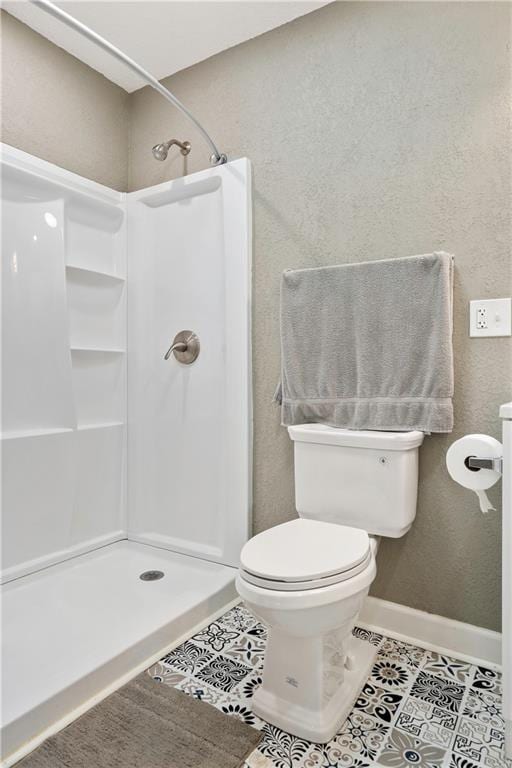 bathroom featuring toilet, a shower, and tile patterned flooring