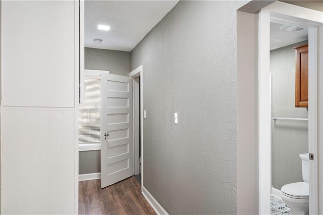 corridor featuring dark wood-type flooring and a textured ceiling