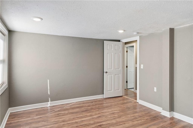 unfurnished room with a textured ceiling and hardwood / wood-style flooring