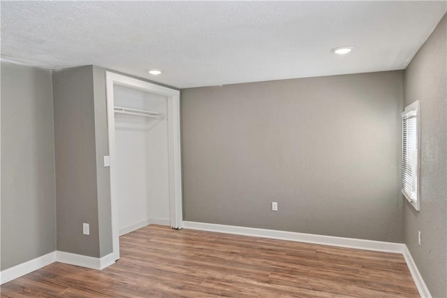 unfurnished bedroom with a textured ceiling, wood-type flooring, and a closet