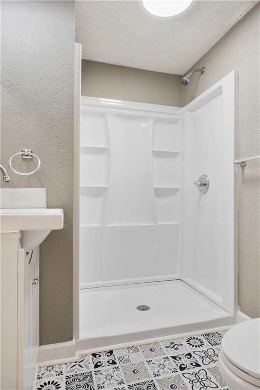 bathroom featuring toilet, vanity, a shower, and tile patterned flooring