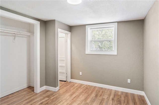 unfurnished bedroom with a closet, a textured ceiling, and light wood-type flooring